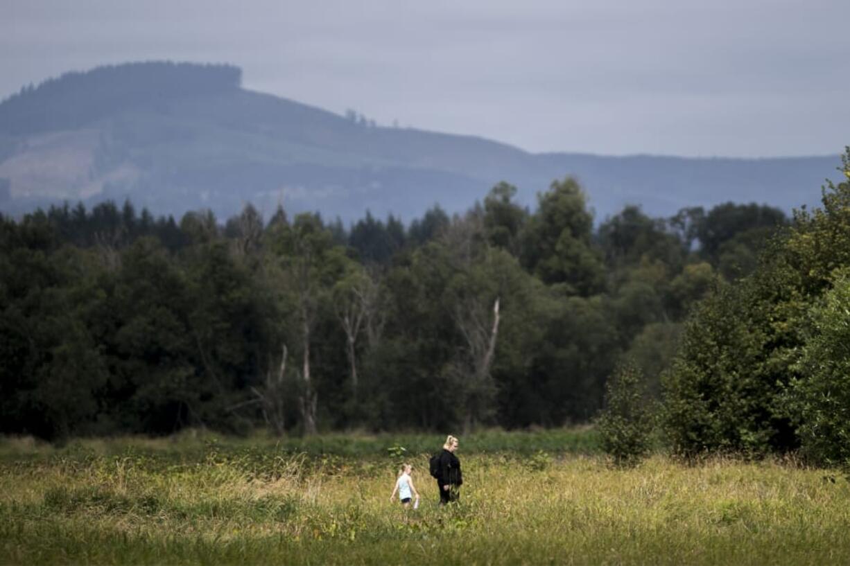 Maxine Deschand, 6, left, and her mother, Brianna Deschand, walk through the Ridgefield National Wildlife Refuge on Thursday. The refuge has proved a crucial habitat for the region’s endangered and threatened species, helping populations such as the Columbian white-tailed deer rebound.