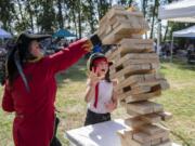 Katie High, left, attempts to brace the falling Jenga tower from hitting her 8-year-old daughter Emma during the Washougal Pirate Festival at Captain William Clark Park on Saturday.