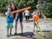 Matthew Lowenstein, 7, left, and his mother Amber, center, spray a water soaker, while his brother Mark, 5, right, watches Tuesday afternoon at Klineline Pond in Vancouver.