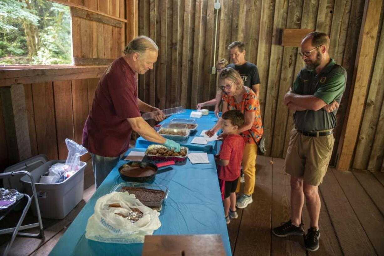 Volunteer John Clapp, left, hands out cookies and other baked goods to guests who were visiting the Cedar Creek Grist Mill on Saturday. The goodies were made off-site with flour milled on-site.