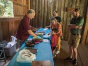 Volunteer John Clapp, left, hands out cookies and other baked goods to guests who were visiting the Cedar Creek Grist Mill on Saturday. The goodies were made off-site with flour milled on-site.