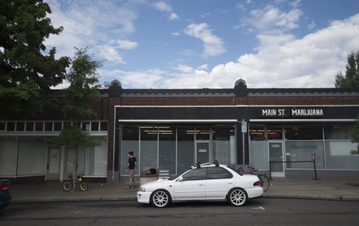 A pedestrian stands outside Main Street Marijuana on Thursday morning. The business purchased its own storefront last month, and now owns the portion of the building with the black window trim. The portion on the left with the white paper in the windows serves as the store’s back room, and is still rented.