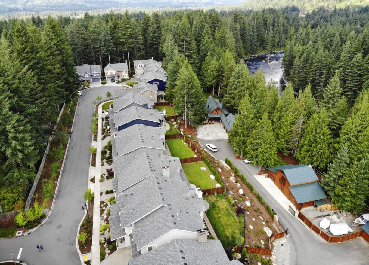 In this photo taken July 24, 2019, a block of houses are carved into a forest along the Middle Fork Snoqualmie River in the Cascade foothills of North Bend, Wash. Experts say global warming is changing the region’s seasons, bringing higher temperatures, lower humidity and longer stretches of drought. And that means wildfire risks in coming years will extend into areas that haven’t experienced major burns in residents’ lifetimes.