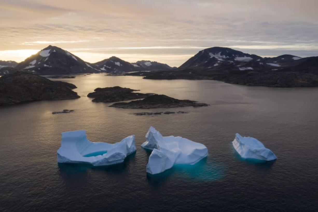 Large Icebergs float away Friday as the sun rises near Kulusuk, Greenland. Scientists are hard at work trying to understand the alarmingly rapid melting of the ice.