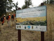 In this July 25, 2019, photo, a fire crew walks past a sign at a proposed site for a wildlife crossing in Agoura Hills, Calif. Hoping to fend off the extinction of mountain lions and other species that require room to roam, transportation officials and conservationists will build a mostly privately funded wildlife crossing over a freeway. It will give big cats, coyotes, deer, lizards, snakes and other creatures a safe route to open space and better access to food and potential mates.