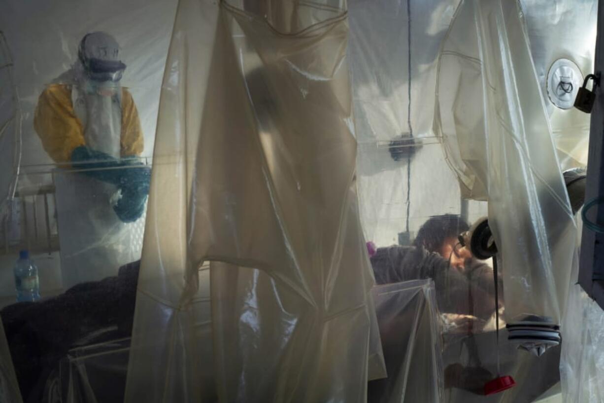 File-In this July 13, 2019 file photo, health workers wearing protective gear check on a patient isolated in a plastic cube at an Ebola treatment center in Beni, Congo. Health authorities in Congo have halted an Ebola treatment study early with good news: Two of the four experimental drugs seem to be saving lives. More than 1,800 people have died in the African country’s yearlong outbreak.