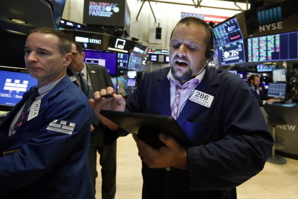 FILE - In this Aug. 19, 2019, file photo specialist Stephen Naughton, left, and trader Michael Milano work on the floor of the New York Stock Exchange. Stocks are opening slightly lower on Wall Street on Tuesday, Aug. 20, as major U.S. indexes give back a bit of the ground they won over the previous three days.