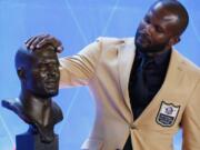 Former NFL player Champ Bailey touches a bust of himself during the induction ceremony at the Pro Football Hall of Fame, Saturday, Aug. 3, 2019, in Canton, Ohio.