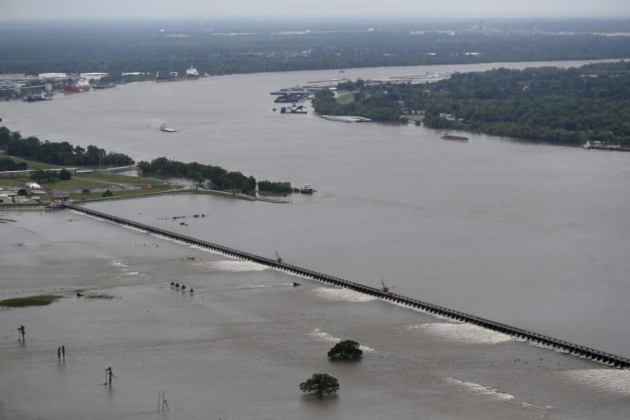 File - In this May 10, 2019 file photo, workers open bays of the Bonnet Carre Spillway, to divert rising water from the Mississippi River to Lake Pontchartrain, upriver from New Orleans, in Norco, La. The river that drains much of the flood-soaked United States is running far higher than normal this hurricane season, menacing New Orleans in multiple ways. One continuing concern is the massive volume of water that for months has been pushing against levees protecting a city that’s mostly below sea level.