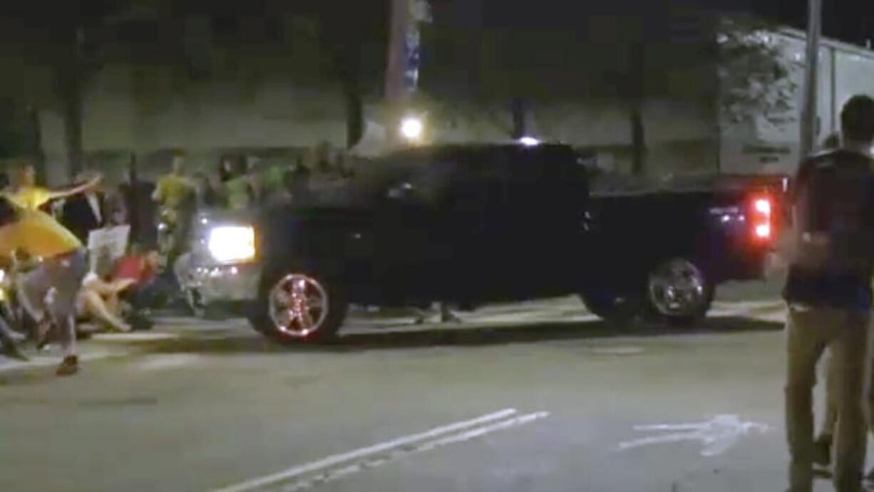 In this still image from video provided by WLNE-TV, protesters blocking an entrance to the Donald W. Wyatt Detention Facility begin to move as a pickup truck approaches, Wednesday night, Aug. 14, 2019, in Central Falls, R.I. The group, which was protesting federal immigration policies, said at least two people were injured. Rhode Island’s attorney general said he is investigating the incident.