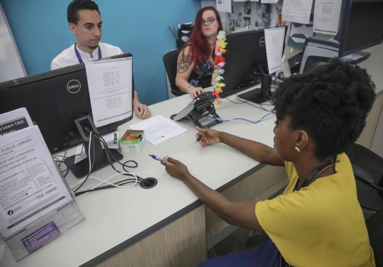 Shantel Johnson, right, a social worker at Queens Central Library, and Michael Montero, left, social work summer intern from NYU, meet at the library’s coordinating desk for adult services in the Queens borough of New York.