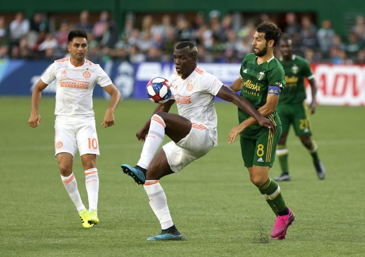 Atlanta United's Florentin Pogba, center, controls the ball as teammate Gonzalo "Pity" Martínez, left, looks on and Portland Timbers' Diego Valeri attempts to maneuver around him during an MLS soccer match host in Portland, Ore., on Sunday, Aug. 18, 2019.