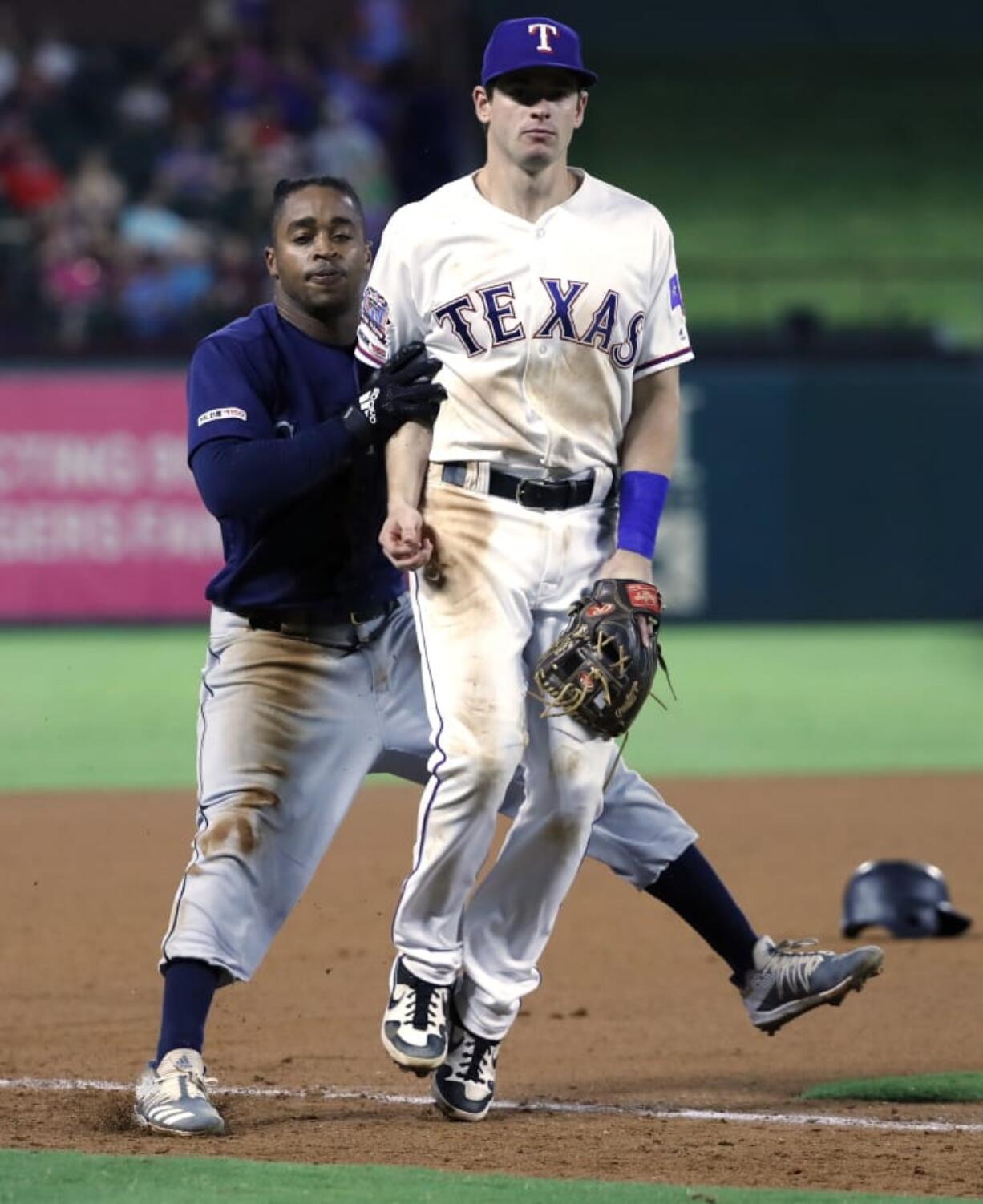 Seattle Mariners’ Mallex Smith, left, runs in to Texas Rangers third baseman Nick Solak as the two look at a ball thrown to Solak by shortstop Elvis Andrus in the seventh inning of a baseball game in Arlington, Texas, Friday, Aug. 30, 2019. Smith, who hit a triple on the play advanced home on the errant throw by Andrus.