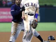 Seattle Mariners’ Mallex Smith, left, runs in to Texas Rangers third baseman Nick Solak as the two look at a ball thrown to Solak by shortstop Elvis Andrus in the seventh inning of a baseball game in Arlington, Texas, Friday, Aug. 30, 2019. Smith, who hit a triple on the play advanced home on the errant throw by Andrus.