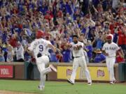 Texas Rangers' Isiah Kiner-Falefa (9) sprints down the first base line after hitting run-scoring single as Elvis Andrus, center, and Emmanuel Clase, right, come out of the dug out celebrating the walk off hit in the ninth inning of a baseball game against the Seattle Mariners in Arlington, Texas, Saturday Aug. 31, 2019. The Rangers won 3-2.