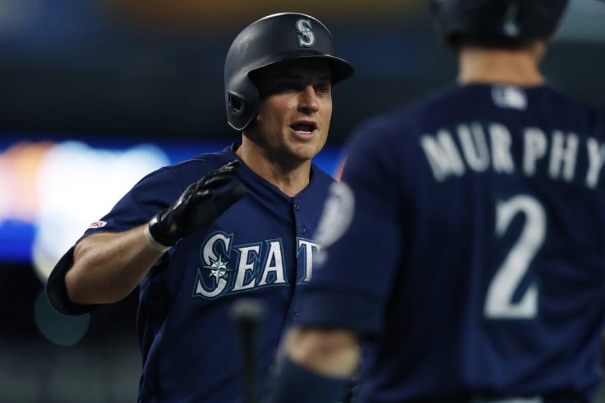 Seattle Mariners' Kyle Seager is greeted at the dugout by teammate Tom Murphy after a three-run home run during the sixth inning of a baseball game against the Detroit Tigers, Tuesday, Aug. 13, 2019, in Detroit.