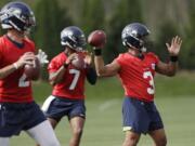 Seattle Seahawks starting quarterback Russell Wilson (3) leads Paxton Lynch (2) and Geno Smith (7) in a quarterbacks drill at an NFL football training camp Thursday, Aug. 1, 2019, in Renton, Wash.