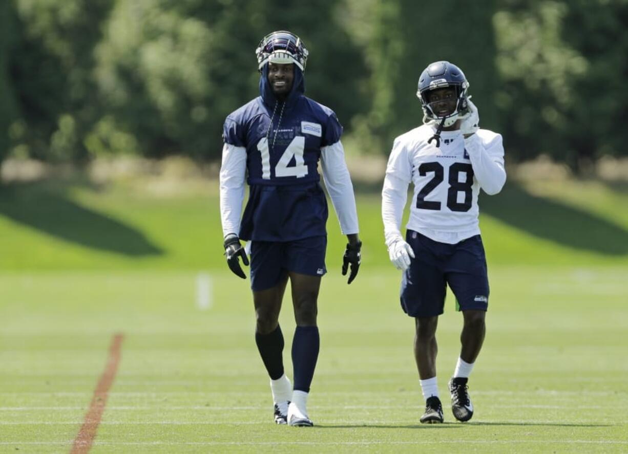 Seattle Seahawks wide receiver DK Metcalf (14) and cornerback Ugo Amadi (28) walk on the field following NFL football training camp, Monday, Aug. 5, 2019, in Renton, Wash. (AP Photo/Ted S.