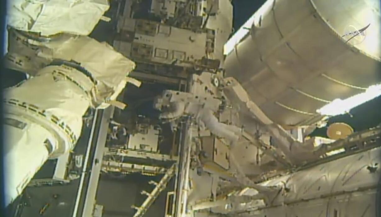 This photo provided by NASA, astronauts Andrew Morgan and Nick Hague (not seen) begin to install a docking port delivered by SpaceX last month outside the International Space Station on Wednesday, Aug. 21, 2019. The port will be used by SpaceX and Boeing once they start launching astronauts to the orbiting lab late this year or early next year.