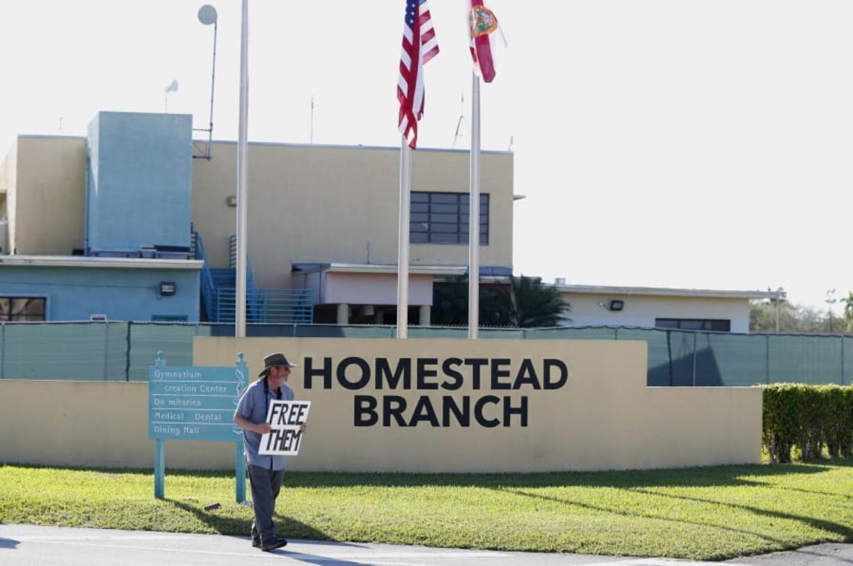 FILE - In this Feb. 19, 2019 file photo, Josh Rubin demonstrates in front of the Homestead Temporary Shelter for Unaccompanied Children, in Homestead, Fla. Federal officials say the Florida detention camp that has housed thousands of migrant children is emptying out. Health and Human Services Department spokeswoman Evelyn Stauffer said in an email Saturday, Aug. 3, that all children are either with family members or at smaller state-licensed facilities.