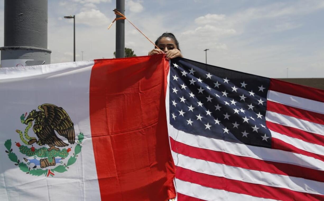 Maylin Reyes hangs a Mexican flag at a makeshift memorial near the scene of a mass shooting at a shopping complex Monday, Aug. 5, 2019, in El Paso, Texas.