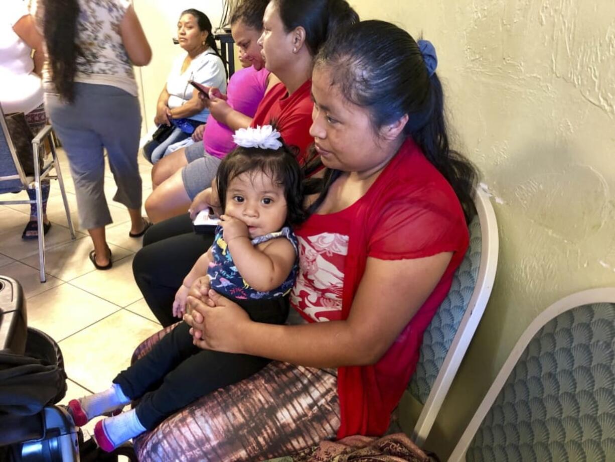 Amalia Godinez sits her 10-month-old daughter Priscila on her lap as she waits for help at the Guatemalan-Maya Center on Friday, Aug. 30, 2019 in Lake Worth, Fla. Godinez said she was worried she would lose power and not be able to cook for her three children. Charity groups are worried about vulnerable populations along the eastern coast, who were still in the cone of potential storm pathway forecast by the National Hurricane Center in Miami.