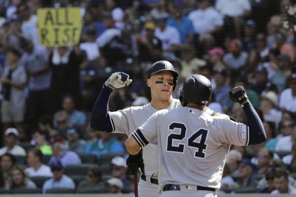 A fan holds a sign that reads “All Rise” as New York Yankees’ Aaron Judge, left, greets Gary Sanchez (24) after Judge hit a two-run home run against the Seattle Mariners during the fifth inning of a baseball game, Wednesday, Aug. 28, 2019, in Seattle. (AP Photo/Ted S.