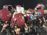 Stevenson players hoist the Gorge Bowl trophy, covered in plastic wrap to protect it from rain, after beating Columbia-White Salmon.