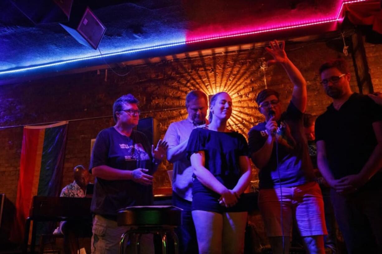 From left, Kelli Harrison, Bob Niehaus, Kelly Ravenscraft, Jennie Garcia and Alex Aivars pray during an Affirming Worship service Aug. 13 at Atmosphere Bar in Chicago.