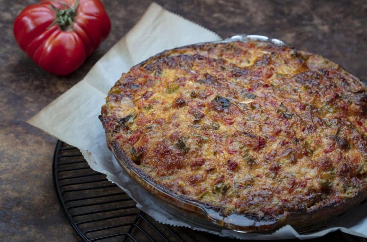 Tomatoes are roasted in the oven to remove most of their water, then layered in a crust with cheese, basil and cracker crumbs and spread with a cheese, pimento and mayo topping.