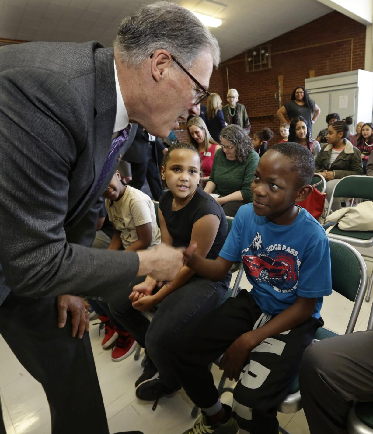 Washington Gov. Jay Inslee, left, shakes hands with Ibrahim Gabinga, 10, before Inslee signed a bill on April 1, 2016, at McCarver Elementary School in Tacoma. (AP Photo/Ted S.