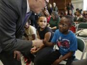 Washington Gov. Jay Inslee, left, shakes hands with Ibrahim Gabinga, 10, before Inslee signed a bill on April 1, 2016, at McCarver Elementary School in Tacoma. (AP Photo/Ted S.