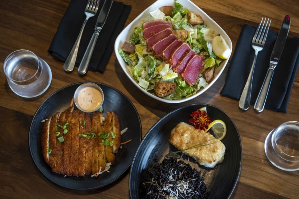 Crispy calamari, bottom left, Ahi Caesar Salad, top center, and Mac Nut Halibut, bottom right, at Tommy O’s at The Camas Hotel.