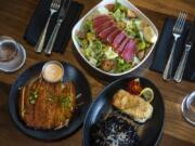 Crispy calamari, bottom left, Ahi Caesar Salad, top center, and Mac Nut Halibut, bottom right, at Tommy O’s at The Camas Hotel.