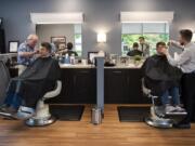 Arlo’s Barber Shop owner Bob Lutz, left, cuts Joshua Skinner’s hair and barber James Howell cuts William Rust’s hair at the shop’s new location in Uptown Vancouver on Friday.