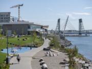 Kathy Bender of Vancouver, bottom left, walks her dog Henry, 4, along the Columbia River at The Waterfront Vancouver early this month.