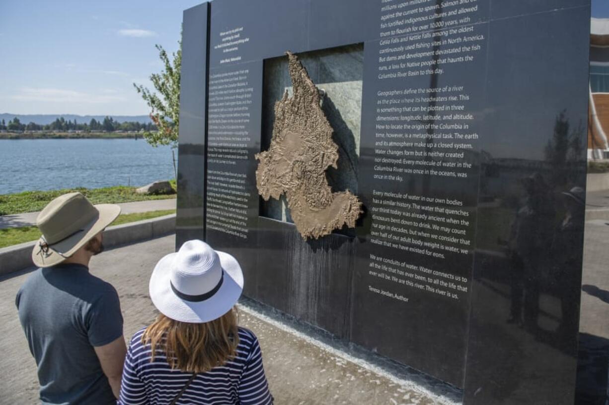 Tom Pearson, left, and Kathryn Pearson of Vancouver examine the Columbia River water feature at The Waterfront Vancouver last week. Water deposits can be seen staining the bottom of the granite and copper monolith after a month of public use.