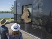 Tom Pearson, left, and Kathryn Pearson of Vancouver examine the Columbia River water feature at The Waterfront Vancouver last week. Water deposits can be seen staining the bottom of the granite and copper monolith after a month of public use.