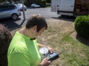 Joe Cryblskey, a Clark Public Utilities automated meter reading driver, uses a manual meter reader to look at customer usage, while covering his route in the Salmon Creek and Felida neighborhoods on Sept. 6. That particular meter was being taken apart for a new electrical panel, causing a failure reading for Cryblskey. Cryblskey said that he has to manually read about 10 meters throughout the day. Cryblskey, 34, has worked for the utility since he graduated high school.