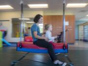 Physical therapist Amy Scott supports Daphne Calvert, 3, who as Rett syndrome, while utilizing a bolster swing during a therapy session at Legacy Salmon Creek Medical Center in Vancouver. Daphne loves to swing. It&#039;s a fun activity she is able to do with Rett.