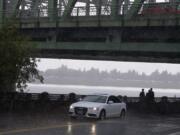 Pedestrians take shelter underneath the Interstate 5 Bridge on Monday afternoon as heavy rains pound the Columbia River waterfront. Expect more unsettled weather Tuesday followed by drier, warmer conditions on Wednesday.