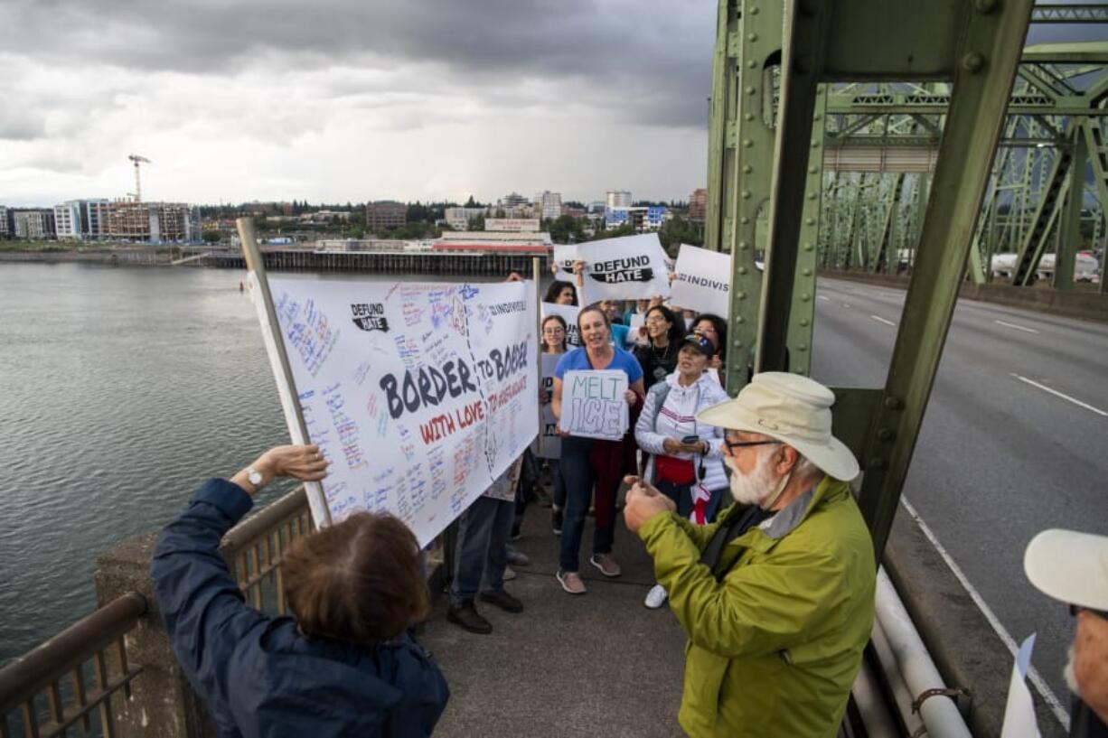 A group from Southwest Washington meets a group from Oregon on Monday night on the Interstate 5 Bridge. The demonstration organized by the left-leaning Indivisible activist group is seeking to reduce the budgets for U.S. Immigration and Customs Enforcement as well as U.S. Customs and Border Protection.