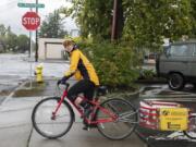 Sally Butts of the Vancouver Bicycle Club checks her left for oncoming traffic before leaving Bike Clark County to pick up leftover produce from the Vancouver Farmers Market on Sunday.