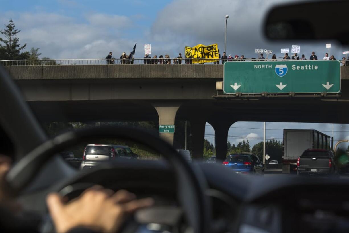 Climate activist Kim Harless honks her horn while driving past fellow demonstrators Friday afternoon on the Evergreen Boulevard overpass on Interstate 5. The event was one of several demonstrations in Vancouver in support of action on climate change.