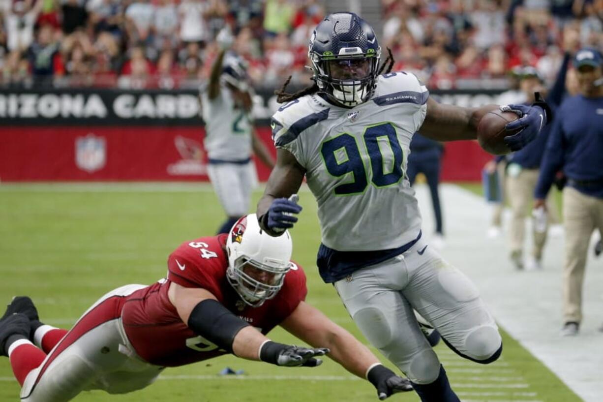 Seattle Seahawks outside linebacker Jadeveon Clowney (90) runs back an interception for a touchdown as Arizona Cardinals offensive guard J.R. Sweezy (64) defends during the first half of an NFL football game, Sunday, Sept. 29, 2019, in Glendale, Ariz.