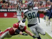 Seattle Seahawks outside linebacker Jadeveon Clowney (90) runs back an interception for a touchdown as Arizona Cardinals offensive guard J.R. Sweezy (64) defends during the first half of an NFL football game, Sunday, Sept. 29, 2019, in Glendale, Ariz.