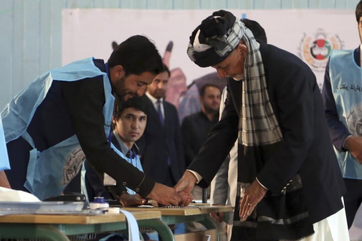 Afghan President Ashraf Ghani, right, inks his finger during the presidential election before he casts his vote at Amani high school, near the presidential palace in Kabul, Afghanistan, Saturday, Sept. 28, 2019. Afghans headed to the polls on Saturday to elect a new president amid high security and Taliban threats to disrupt the elections, with the rebels warning citizens to stay home or risk being hurt.