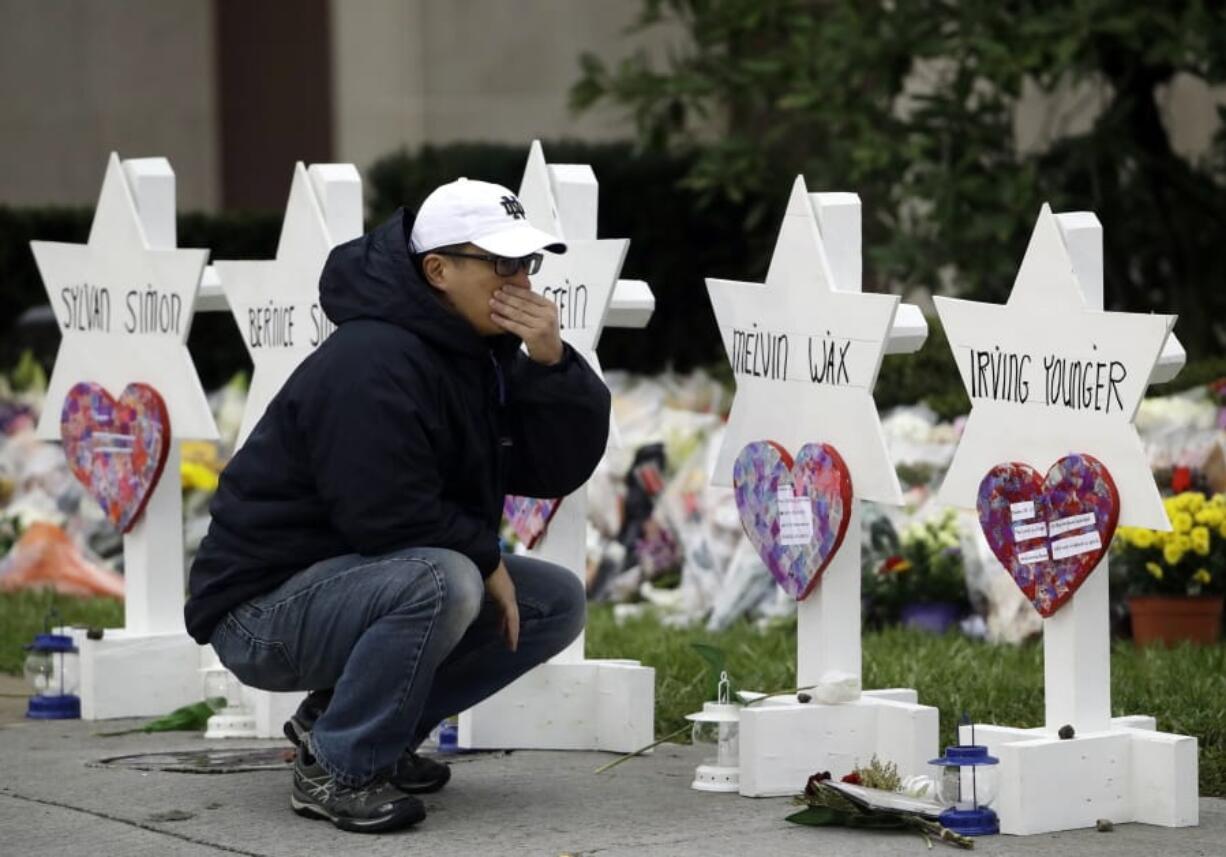 FILE - In this Oct. 29, 2018, file photo, a person pauses in front of Stars of David with the names of those killed in a deadly shooting at the Tree of Life Synagogue, in Pittsburgh. The two mass shootings and a presidential tweet put a spotlight on the idea of “domestic terrorism,” adding momentum to a debate about whether such attacks should be classified and tried in the same way as crimes against America by foreign terrorist groups and their supporters.