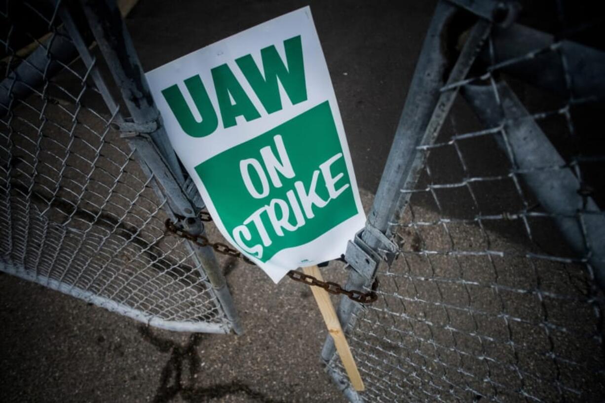 A United Auto Workers strike sign rests between the chains of a locked gate entrance Sept. 16 outside of Flint Engine Operations in Flint, Mich.