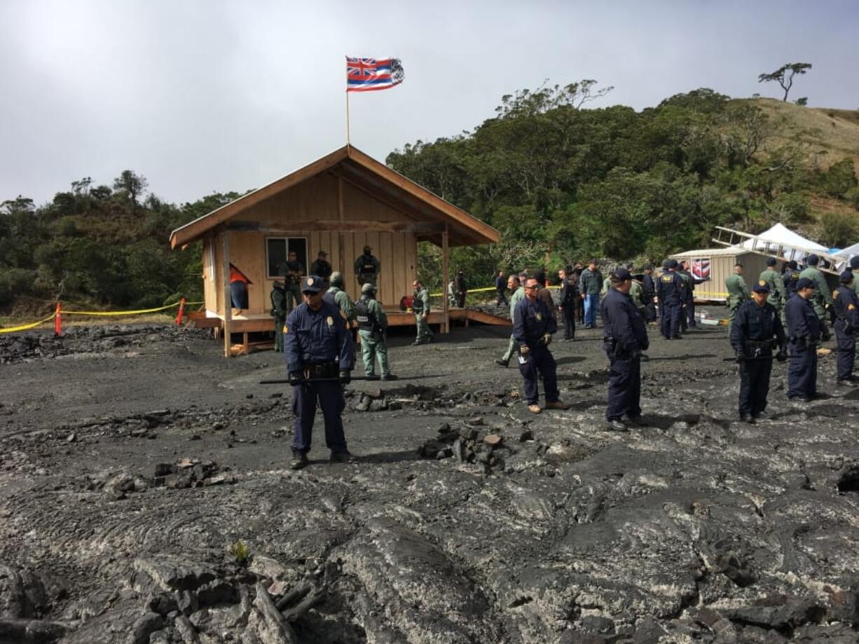 Crews and police gather at a lava field on Hawaii’s Mauna Kea on the big island on Friday, Sept. 6, 2019 while a small wooden house is demolished. Opponents of a giant telescope built the unpermitted structure near their protest camp.